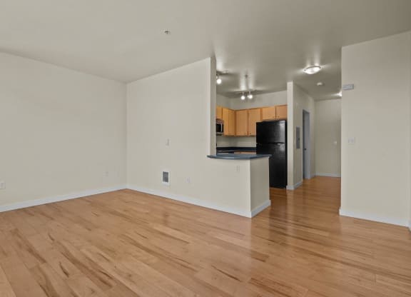 View of kitchen from living room with wood-style flooring and white walls at Collins Circle apartments in the Goose Hollow district in Portland, Oregon.