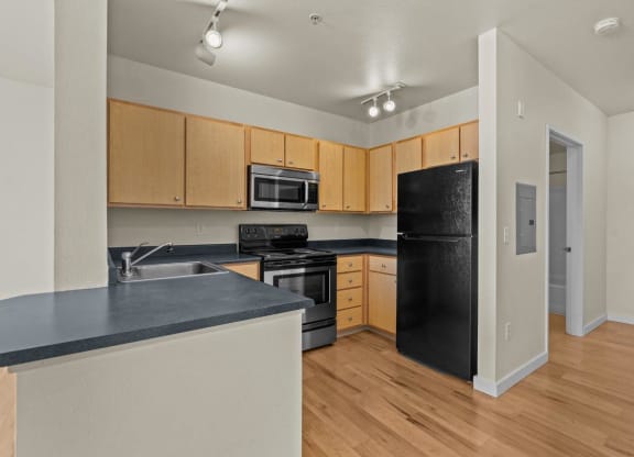 Kitchen with overhead lighting, wood-style flooring, and wooden cabinets at Collins Circle apartments in the Goose Hollow district in Portland, Oregon.