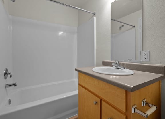 Bathroom with full tub/shower combo and white walls at Collins Circle apartments in the Goose Hollow district in Portland, Oregon.