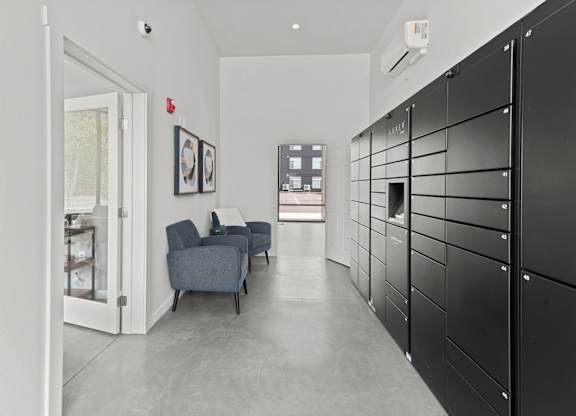 A hallway with black lockers on the right and a blue couch in the middle.