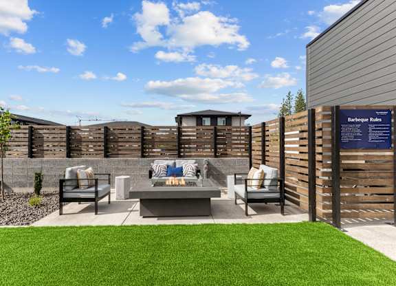 A backyard with a wooden fence and a barbeque grill.
