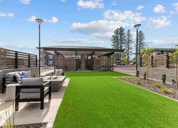 A modern outdoor seating area with a green lawn and a concrete bench.