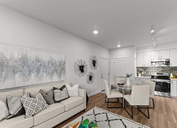 A modern living room with a large painting on the wall and a kitchen area in the background.