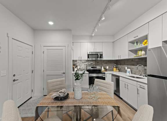 A modern kitchen with a dining table set for two.