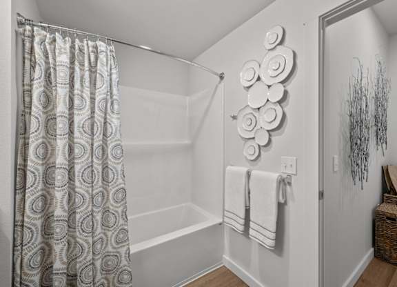 A bathroom with a shower, towel rack, and a decorative wall piece.