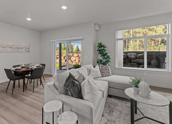 A living room with a grey couch, a black table, and a painting on the wall.