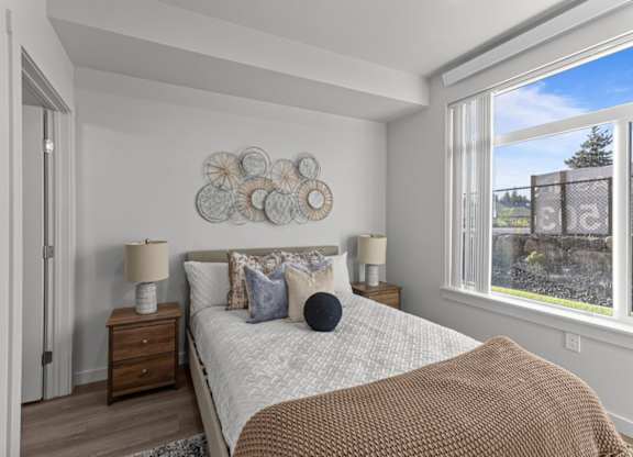 A bedroom with a large bed, a wooden nightstand, and a window overlooking a stone wall.