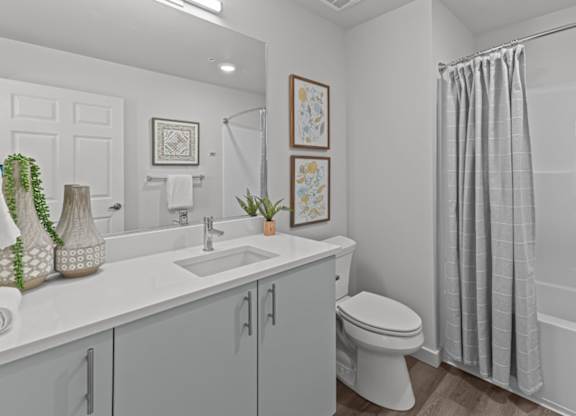A white bathroom with a toilet, sink, and shower.