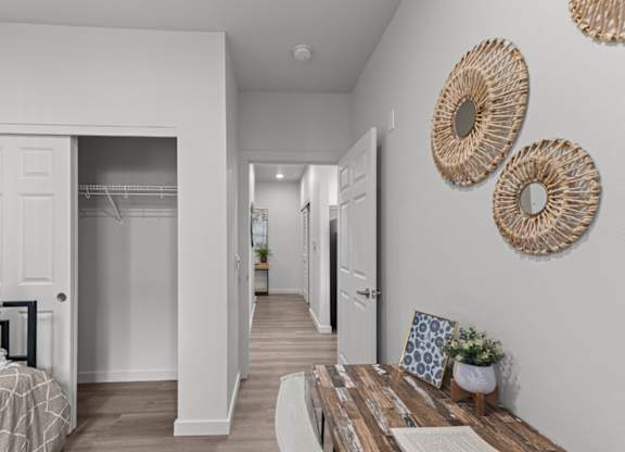 A white hallway with a wooden table and two woven wall hangings.