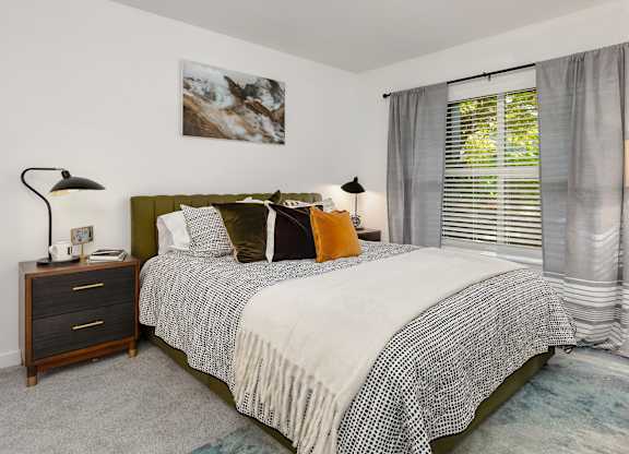 A bedroom with a bed, nightstand, and a painting on the wall.