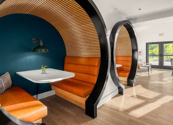A modern dining area with a round table and orange chairs.