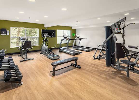 A gym with a variety of equipment including treadmills, stationary bikes, and weight machines.