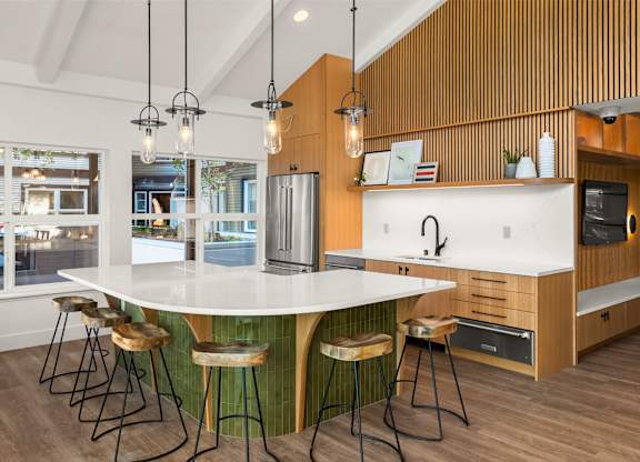A kitchen with a white island and wooden bar stools.