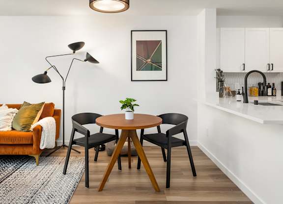 A living room with a brown table and chairs, a couch, and a framed picture on the wall.