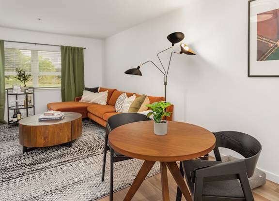 A living room with a brown table, a black chair, a brown sofa, and a black floor lamp.