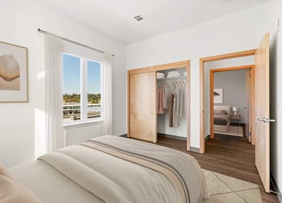 A bedroom with a large bed and a view of trees outside the window.