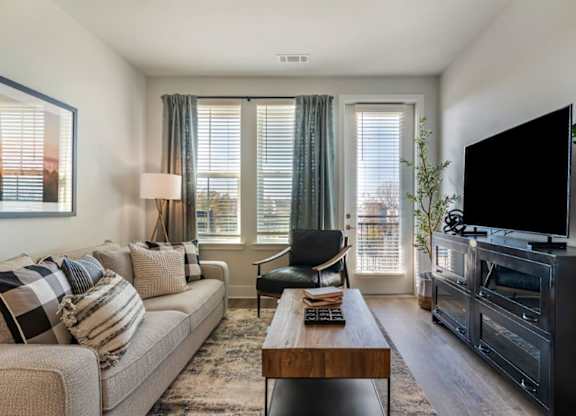 A living room with a couch, a chair, a coffee table, and a television.