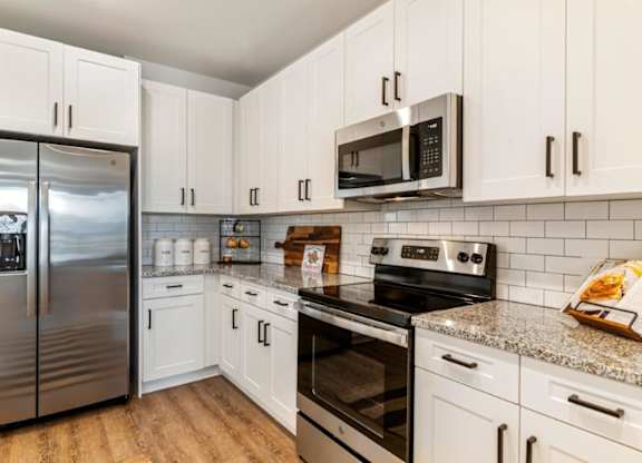 A kitchen with white cabinets and a stainless steel refrigerator.