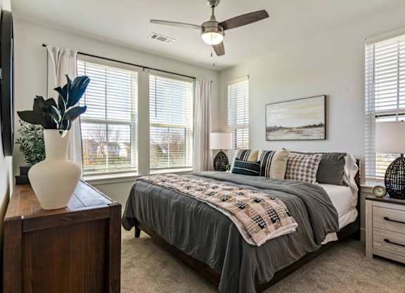 A bedroom with a bed, a dresser, and a ceiling fan.