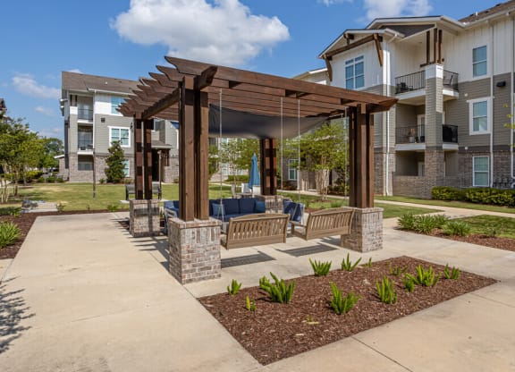 a gazebo with a swing set in front of an apartment building