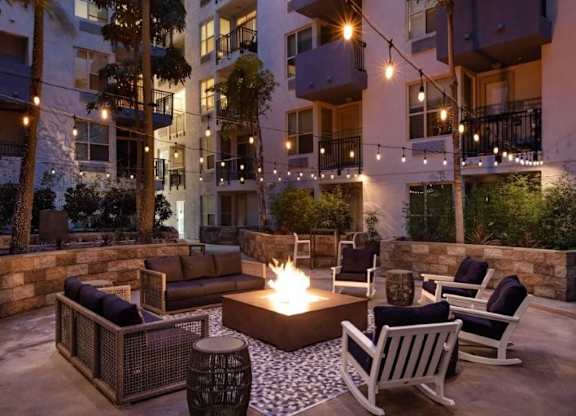 A patio with a fire pit surrounded by chairs and a table.