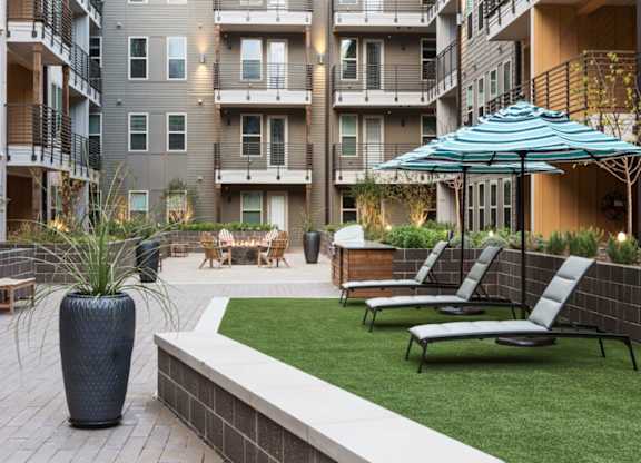 A patio with chairs and a vase is surrounded by apartment buildings.