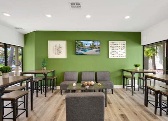A room with green walls and wooden floors has a couch, chairs, and a table.