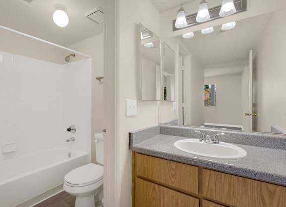 A bathroom with a toilet, sink, and mirror.
