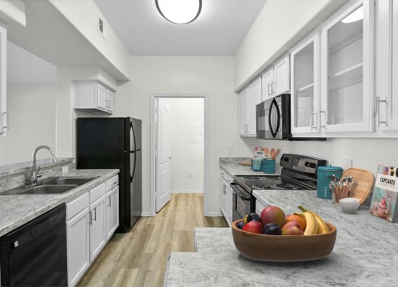 a kitchen with white cabinets and black appliances and a bowl of fruit
