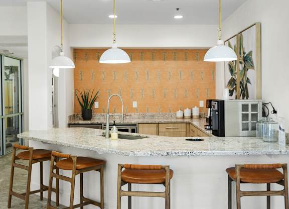 A kitchen with a marble countertop and wooden bar stools.