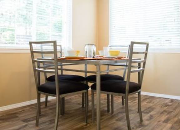 a table and chairs in a room with two windows
