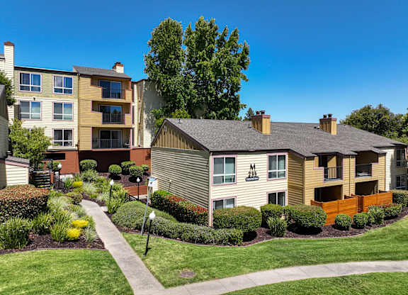 A row of apartment buildings with a walkway in front.