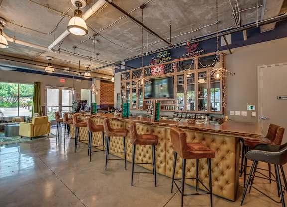A bar with a row of stools in front of it. at Discovery at The Realm, Lewisville, TX