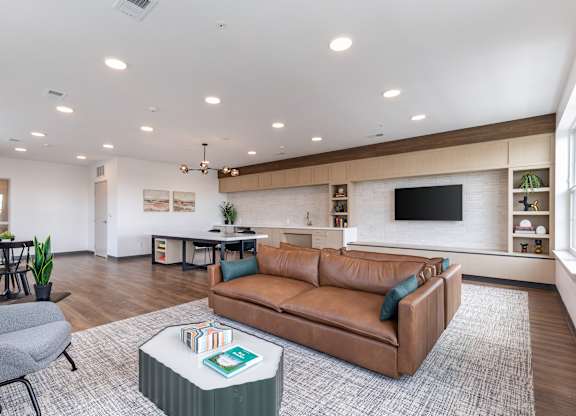 A living room with a brown leather couch and a grey armchair.
