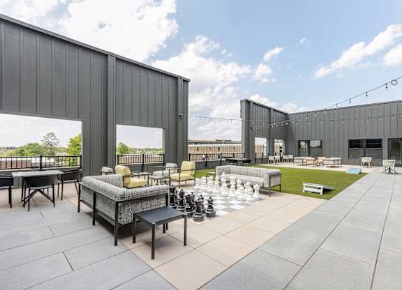 A modern outdoor seating area with a chess board and chairs.