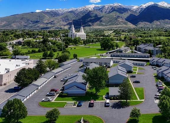 A large white building with a green lawn in front and mountains in the background.