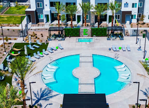 A large blue and white pool surrounded by palm trees and lounge chairs.