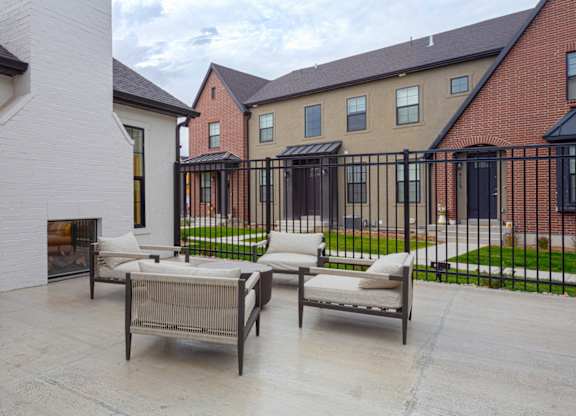 A patio with a table and chairs is in front of a brick building.