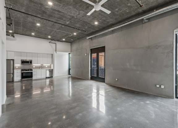 A spacious, empty room with a ceiling fan and a view of the outdoors through a glass door.