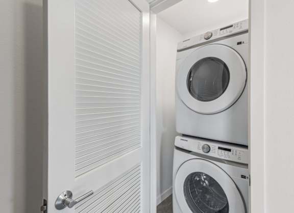 A white door is open to a laundry room with two washing machines.