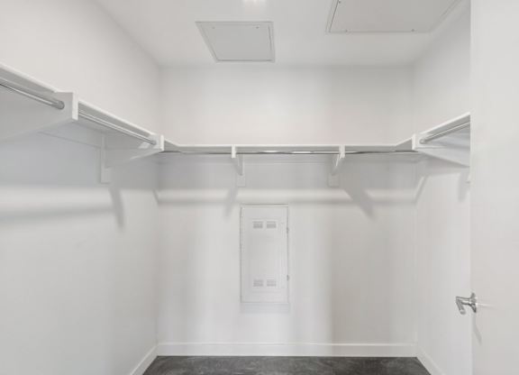 A white closet with a door and a shelf.