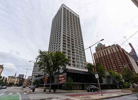 A tall building with a glass facade stands in the middle of a city street.