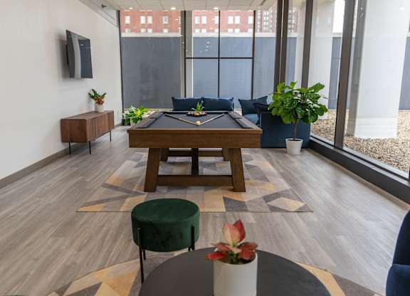 A room with a pool table and a green ottoman.
