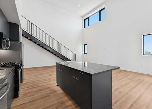 A modern kitchen with a wooden floor and a stainless steel refrigerator.