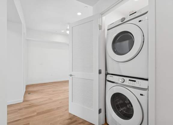 A white laundry room with a washer and dryer stacked on top of each other.