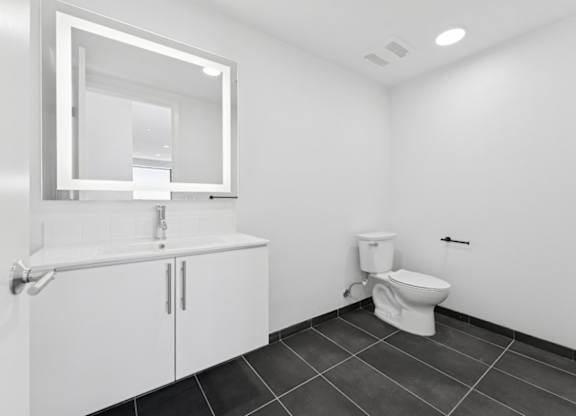 A white bathroom with a toilet, sink, and mirror.
