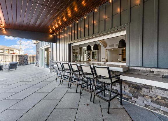 a patio with a bar and chairs in front of a building