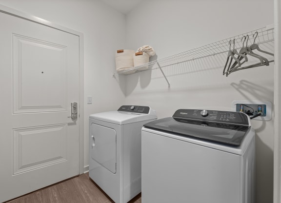 a laundry room with two washers and dryers and a door to a closet