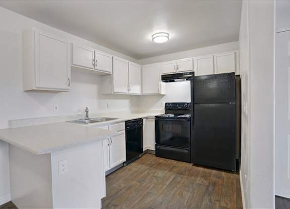 A kitchen with black appliances and white cabinets.