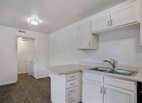 A kitchen with white cabinets and a sink.